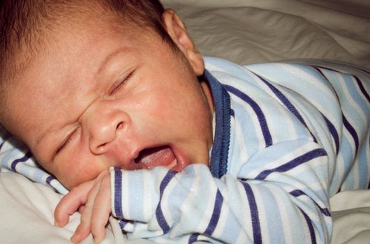 two weeks old newborn baby boy sleeping on white sheet, close up