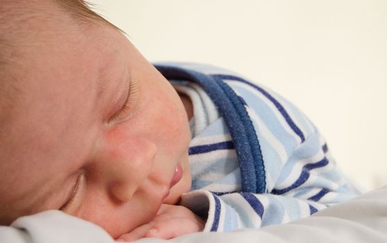 two weeks old newborn baby boy sleeping on white sheet, close up