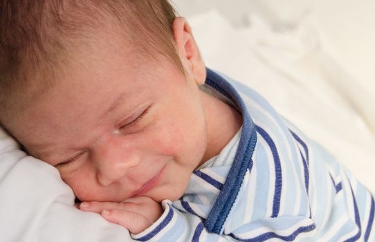 two weeks old newborn baby boy smilleing while sleeping close up