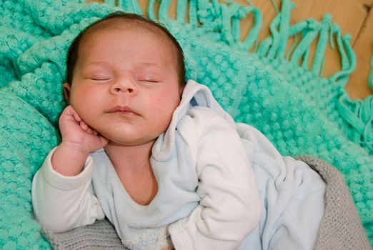 4 weeks old newborn baby boy on green blanket sleeping