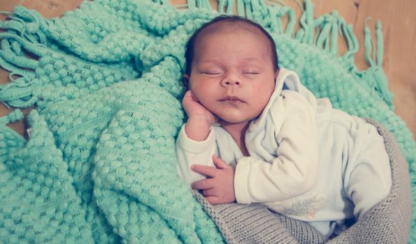 4 weeks old newborn baby boy on green blanket sleeping