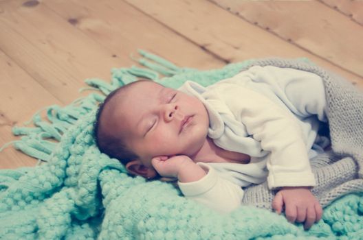 4 weeks old newborn baby boy on green blanket sleeping