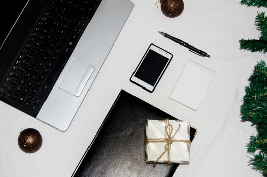 White office desk table with blank notebook, laptop and other office supplies. Top view with copy space, flat lay.