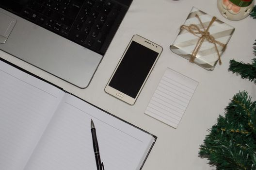 White office desk table with blank notebook, laptop and other office supplies. Top view with copy space, flat lay.