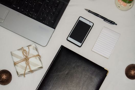 White office desk table with blank notebook, laptop and other office supplies. Top view with copy space, flat lay.