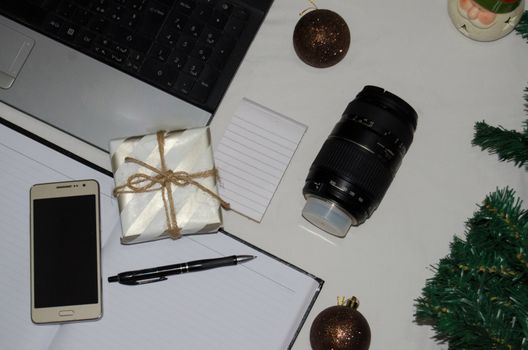 White office desk table with blank notebook, laptop and other office supplies. Top view with copy space, flat lay.