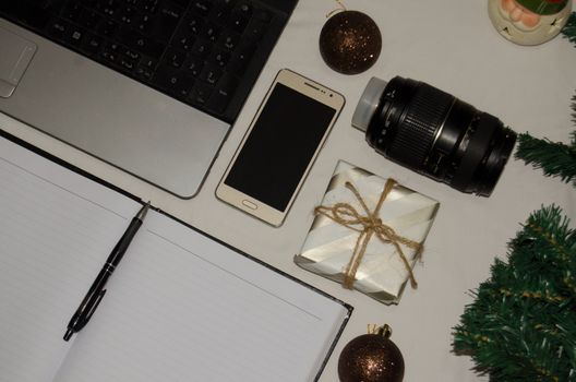 White office desk table with blank notebook, laptop and other office supplies. Top view with copy space, flat lay.