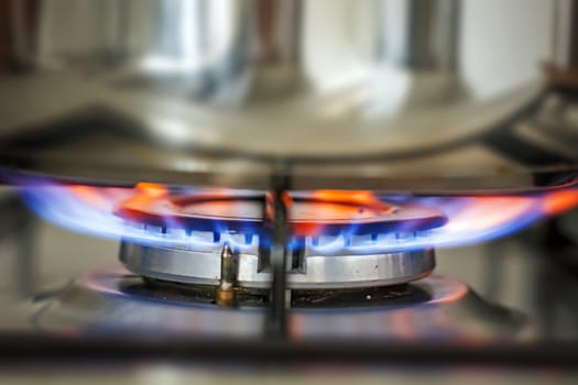 Blue glowing flame burning from the kitchen cooker. Gas and fire. Cooking concept. Interior domestic shot