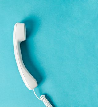 White office desk phone on blue background with free space for your text or message.