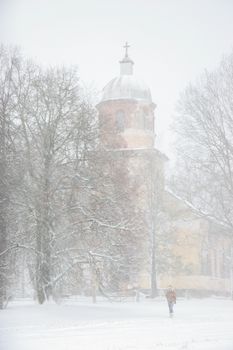 Church in snowfall. Winter in Vecsaule, Latvia. Church covered in snow. Winter scene with snow covered church and trees.



