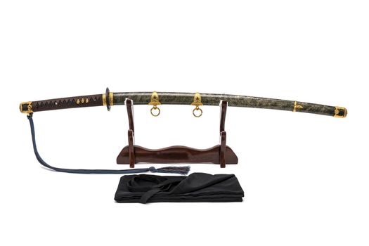 'Kai Gunto' : Japanese Marine Sword From World War 2 with scabbard wrapped by ray skin on wooden stand and bag in front of, isolated in white background.