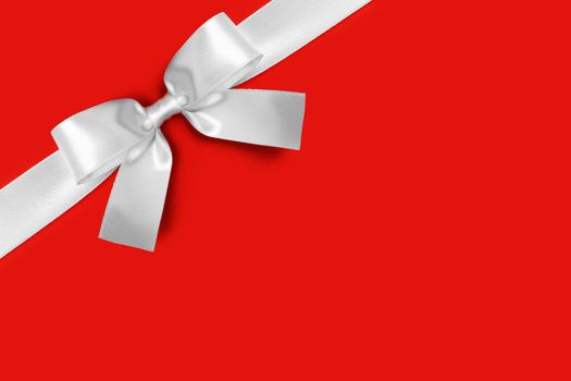 Shiny white satin ribbon and bow on red background. Holiday gift concept