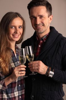 Happy mature couple in casual clothes embracing and clinking glasses of champagne