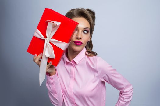 Happy beautiful funny woman holding gift box, listening