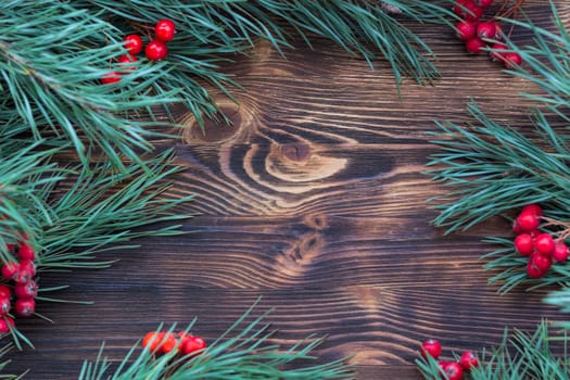 Christmas and New Year seasonal wooden background with pine tree branches and red rowan berries, copy space