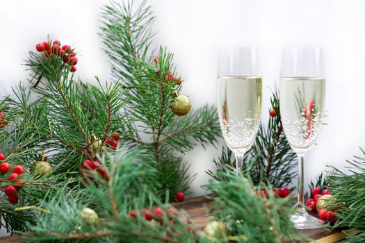 Christmas and New Year seasonal composition with pine tree branches, two glasses of champaign, golden balls ornament and red rowan berries