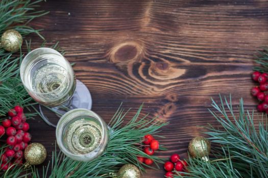 Christmas and New Year seasonal composition with pine tree branches, two glasses of champaign, golden balls ornament and red rowan berries