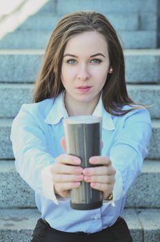 Business woman sitting on the steps during the lunch break, and offers to drink a hot Cup, clouse-up