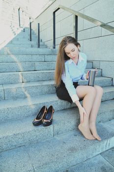 Business woman, during the break, sat down on the steps to stretch her legs, after a hard day's work