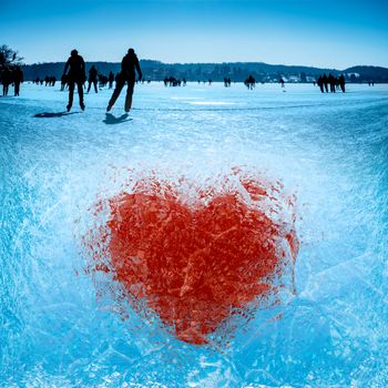 Ice-frozen heart on a lake with skaters