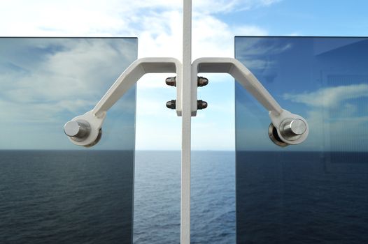 Sea view from the open deck of a modern cruise ship through a strong glass wall.