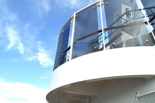 Open deck luxury cruise liner, against the blue sky, a view of the glass fence below.