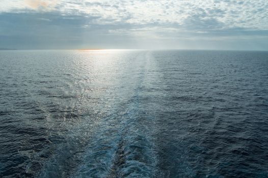 Traces of waves and foam on the surface of the blue sea with a copy of the space at sunset.