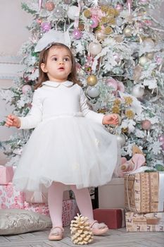 Merry Christmas and Happy Holidays ! Cute funny little child girl near decorated Christmas tree indoors