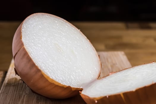Closeup of a sliced onion on a table with dark background
