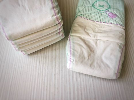 Stacked baby diaper on a white wooden table.