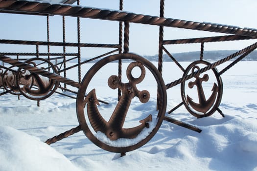 Iron sign of ancor on winter coast covered with white snow