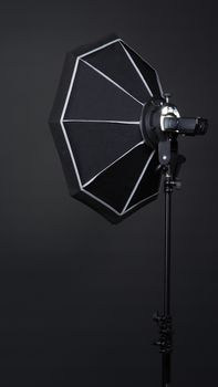 Professional photo studio soft box and flash on the tripod for stillphoto or video production which ready for shape the light for softer, harder or sharper by crew team before shooting on black background.