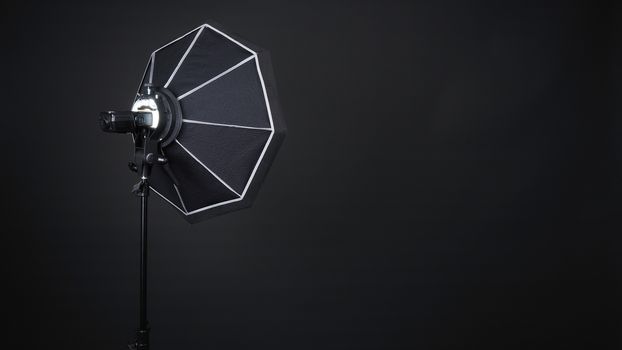 Professional photo studio soft box and flash on the tripod for stillphoto or video production which ready for shape the light for softer, harder or sharper by crew team before shooting on black background.