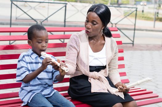 This woman teaches a child to play the flute ln public space.