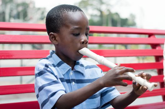 This child sitting on the bench trains on flute.