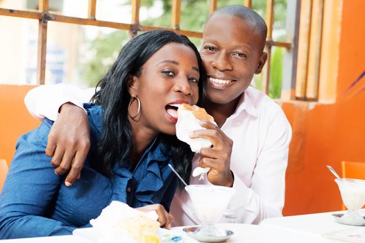 This happy young man put the bread in the mouth of his wife.