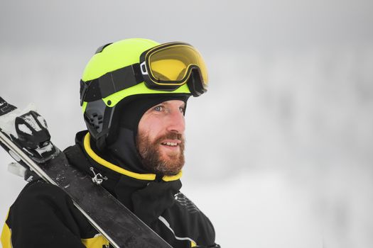 Portrait of a happy male skier in the alps with ski on shoulder