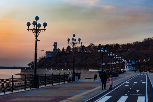 Sunset on the embankment of the Amur river in Khabarovsk. The sun set over the horizon. The embankment is lit by lanterns.