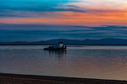 Sunset on the embankment of the Amur river in Khabarovsk. The sun set over the horizon. The embankment is lit by lanterns.