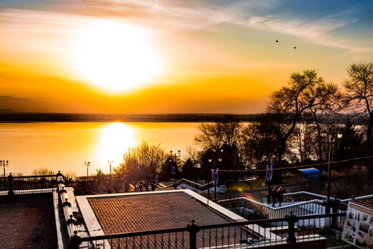 Sunset on the embankment of the Amur river in Khabarovsk. The sun set over the horizon. The embankment is lit by lanterns.