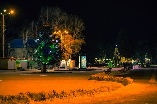 The largest artificial skating rink in the far East of Russia. At night. Many Christmas trees decorated with bright lights.