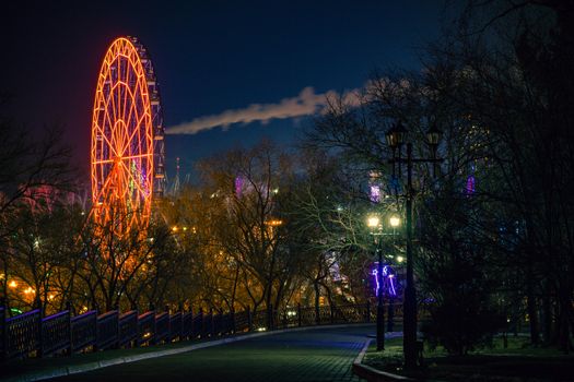 Ferris wheel on the banks of the Amur river in Khabarovsk against the night sky. A bright illumination. Photographed at long exposure.