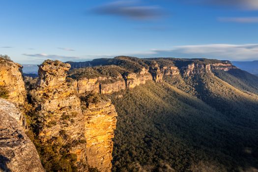 Scenic views of late afternoon sunlight on Narrowneck plateau which divides the Jamison and Megalong valleys in the Blue Mountains, Australia.  In the foreground a rocky cliff known as Boars Head