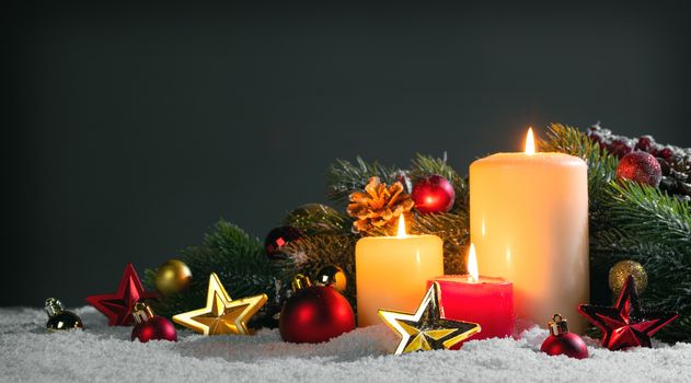 Christmas candles with traditional decorative stars , red baubles , pine cones and green branches on snow