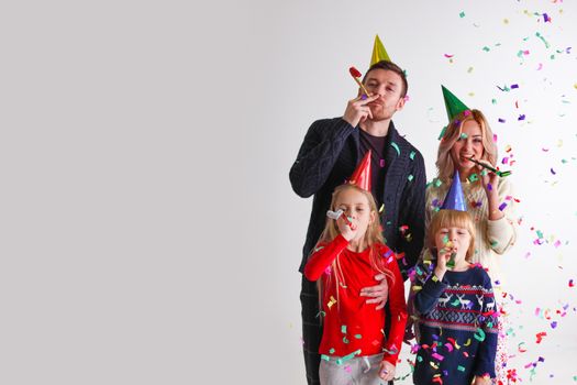 Family blowing party trumpets with confetti celebrating new year