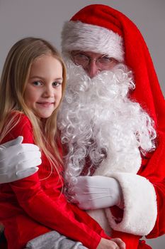 Portrait of smiling little girl sitting on santa claus knees