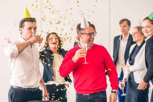 Business people celebrating victory at office party holding glasses of champagne
