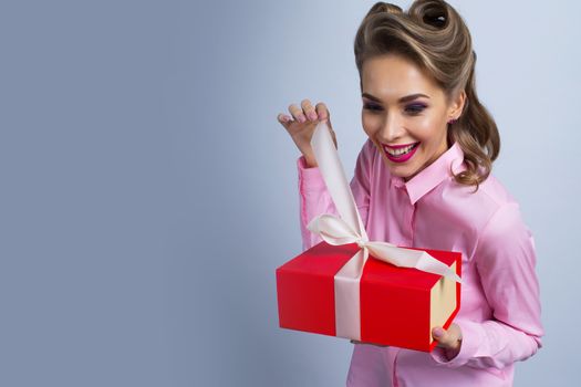 Happy beautiful funny woman unwrapping gift box