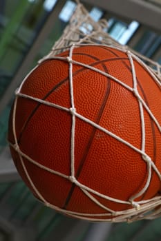 Close up one basketball ball hanging in mesh sack, low angle side view