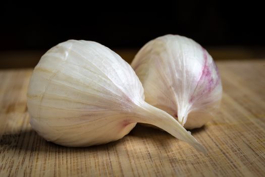 Closeup of two fresh garlic clove on a table with dark background